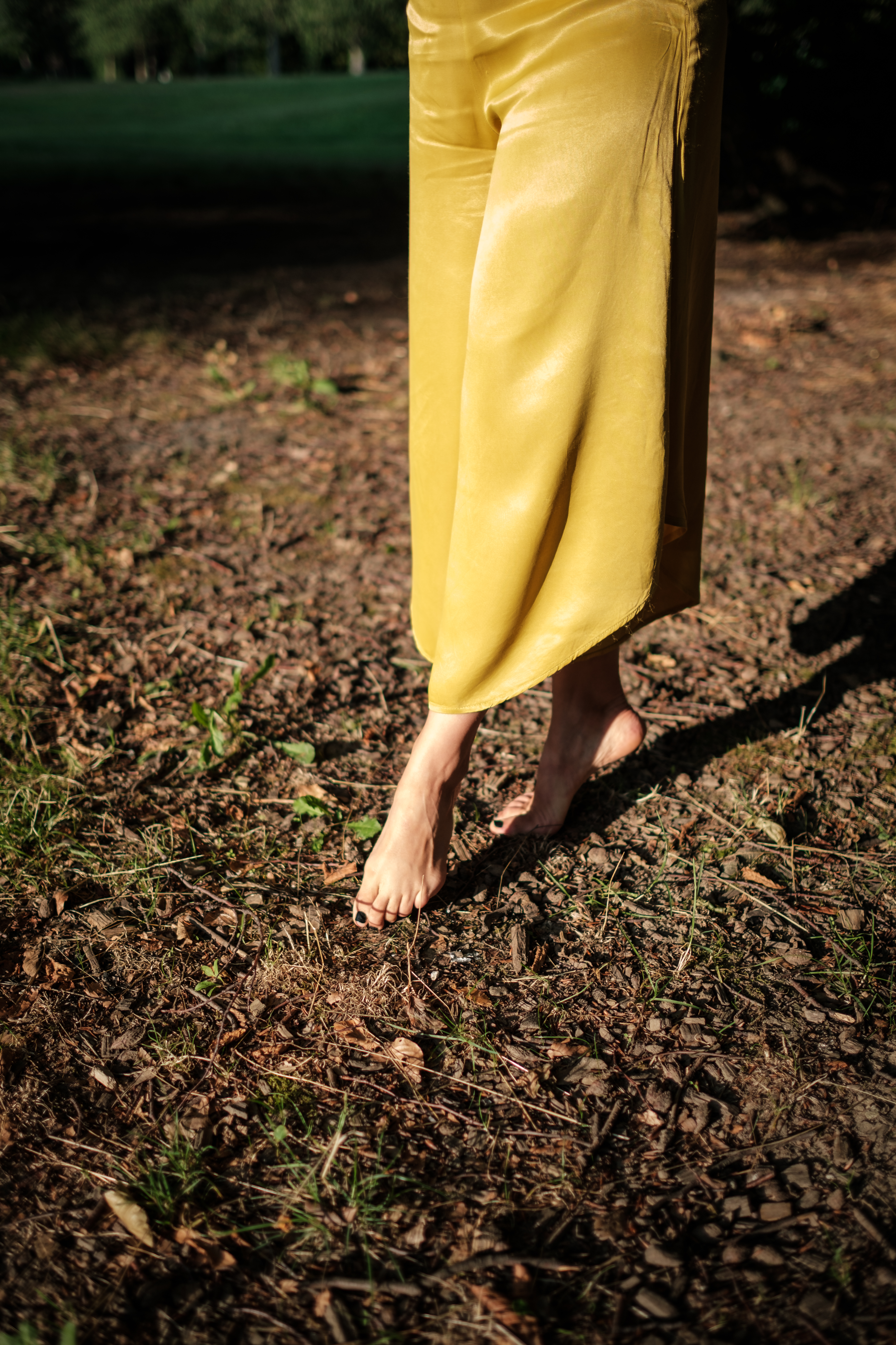 Tânia en robe jaune, pieds nus sur la terre